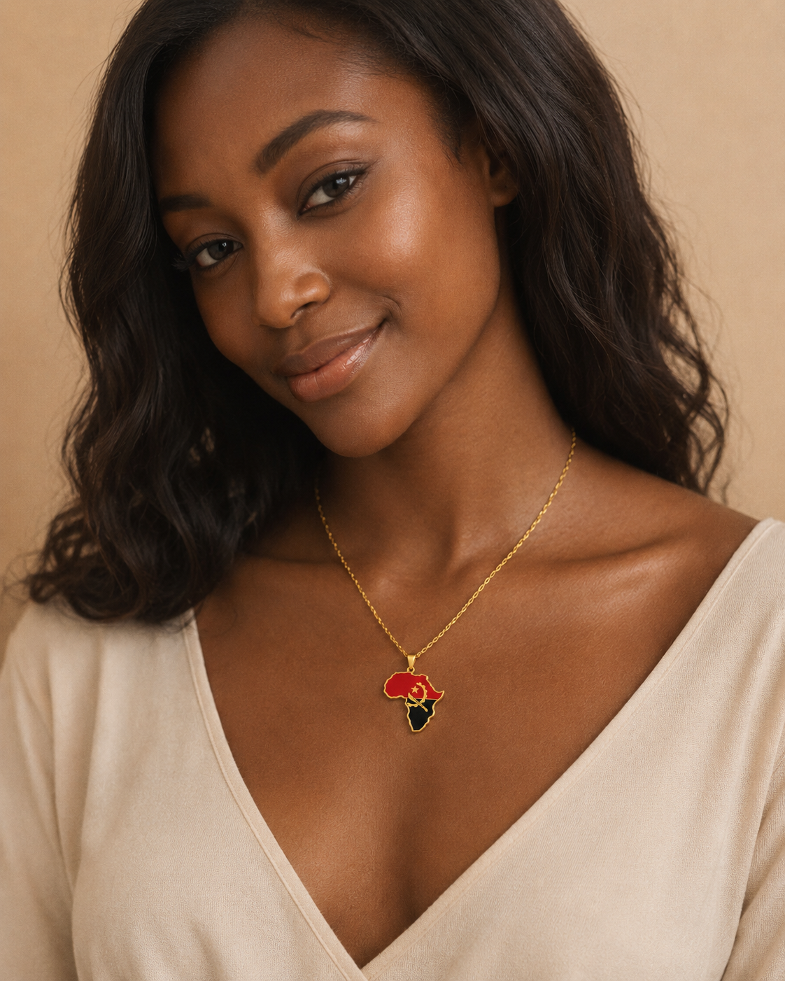 Goldene Afrika-Kontinent-Halskette mit Angola-Flaggenfarben Rot, Schwarz und goldenem Emblem – getragen von einer jungen Frau im beigen Top, Studio-Porträt vor warmem Hintergrund
