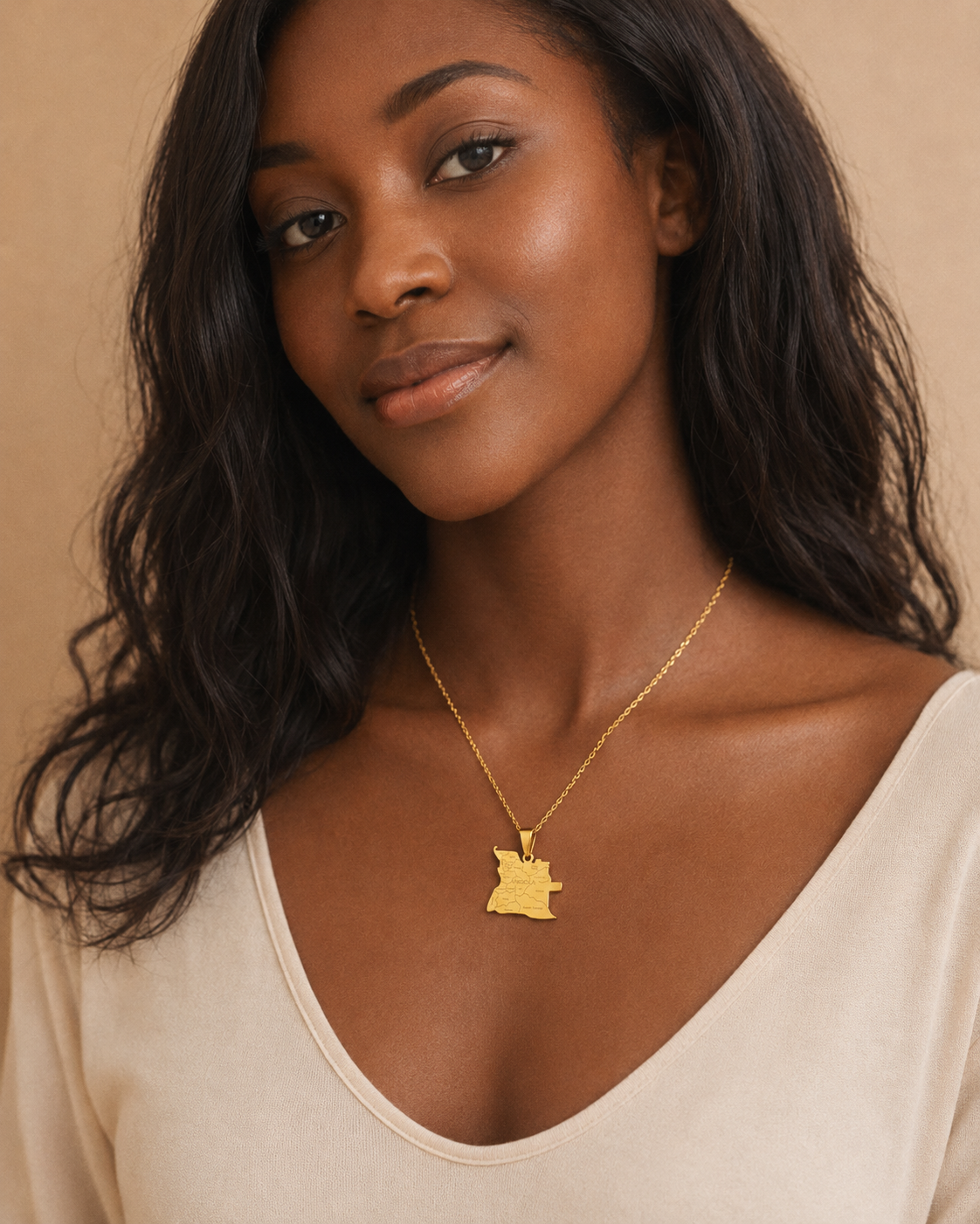 Goldene Angola-Karten-Halskette mit gravierten Provinznamen und Grenzen aus Edelstahl – getragen von einer jungen Frau im beigen Top, Studio-Porträt vor warmem Hintergrund