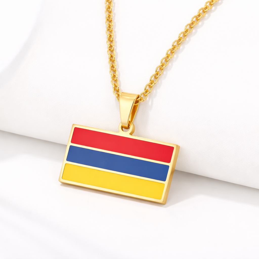 Goldene Halskette mit armenischem Flaggen-Anhänger in den Landesfarben Rot, Blau und Gelb, auf hellem Hintergrund liegend