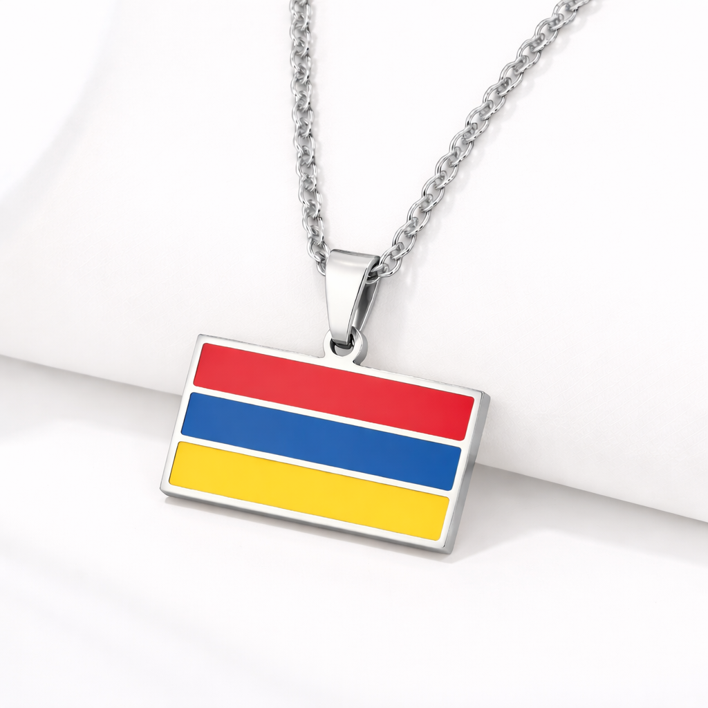 Silberne Halskette mit armenischem Flaggen-Anhänger in den Landesfarben Rot, Blau und Gelb, auf hellem Hintergrund liegend