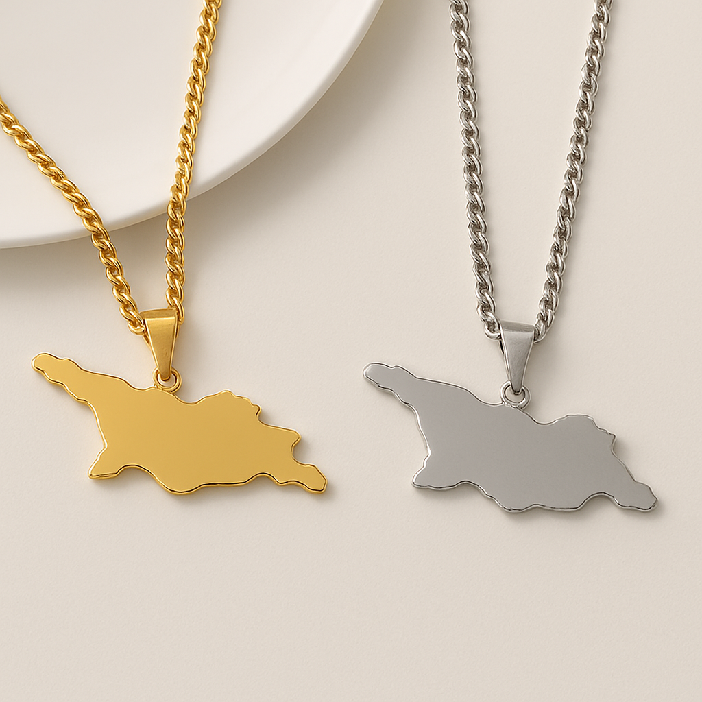 Zwei schlichte Georgien-Karten-Halsketten aus Edelstahl mit Panzerkette – eine in Gold und eine in Silber – nebeneinander auf hellem Hintergrund
