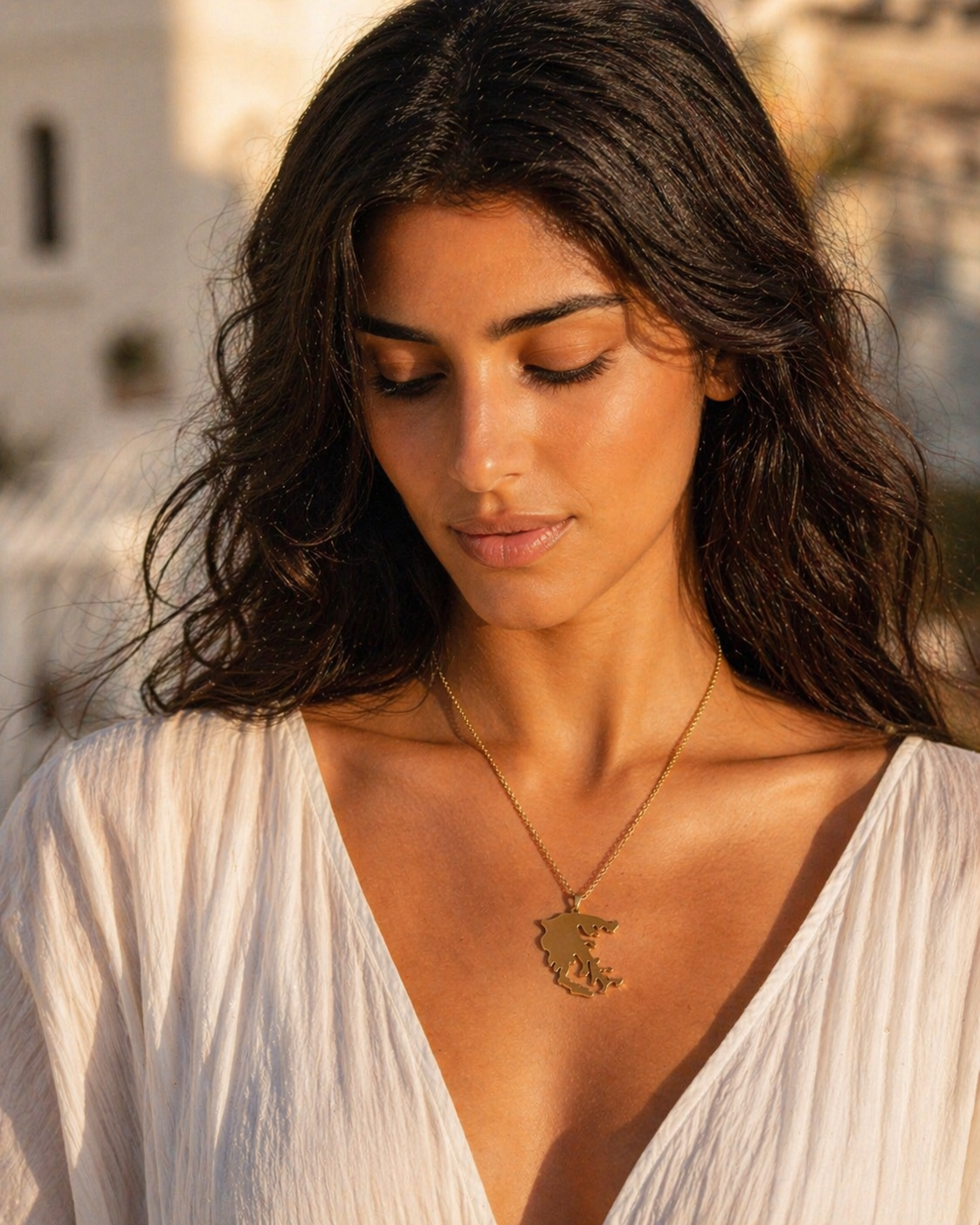 Griechenland Silhouette Halskette in Gold – Frau trägt minimalistischen Anhänger mit griechischer Landkarte im mediterranen Sonnenuntergang