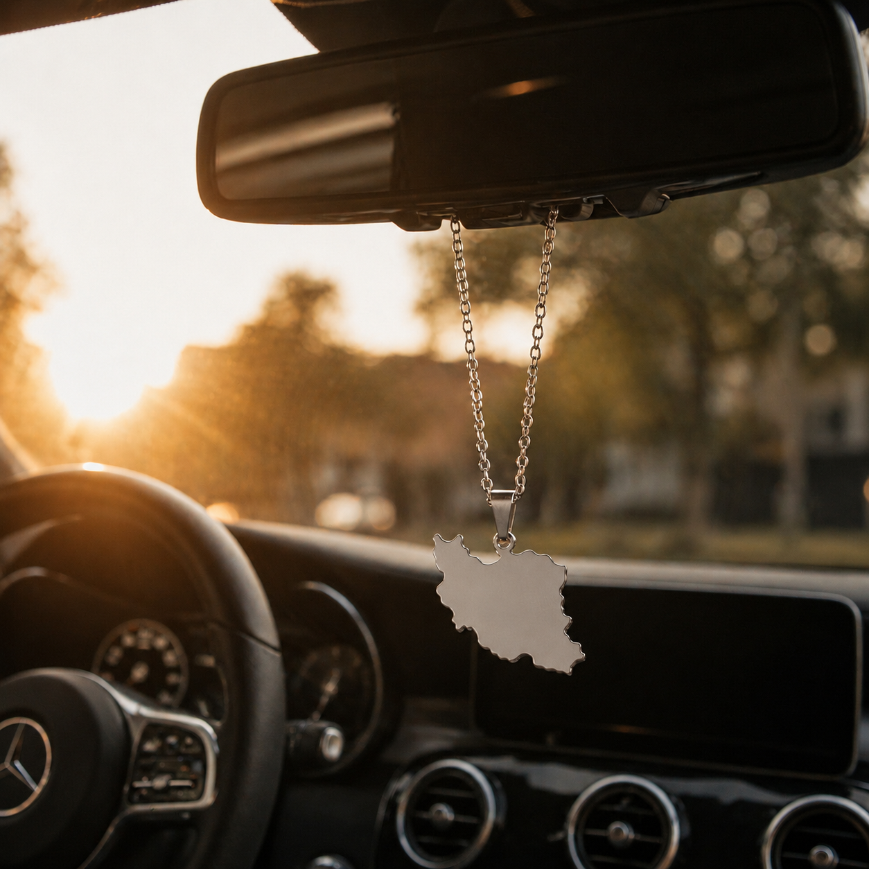 Schlichter silberner Iran-Karten-Anhänger aus Edelstahl, am Rückspiegel eines Mercedes befestigt, Sonnenuntergangsstimmung im Auto
