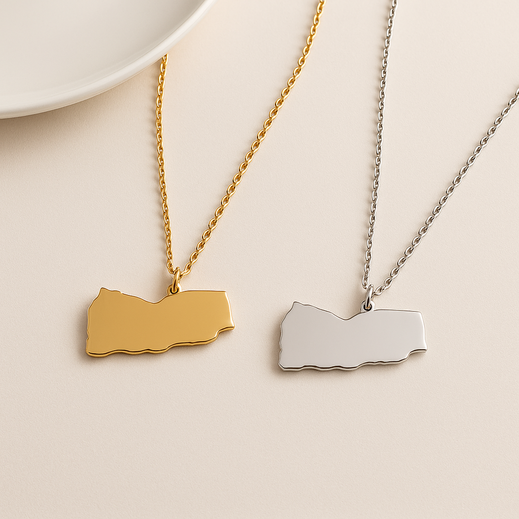 Zwei schlichte Jemen-Karten-Halsketten aus Edelstahl – eine in Gold und eine in Silber – nebeneinander auf hellem Hintergrund