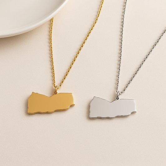 Zwei schlichte Jemen-Karten-Halsketten aus Edelstahl – eine in Gold und eine in Silber – nebeneinander auf hellem Hintergrund
