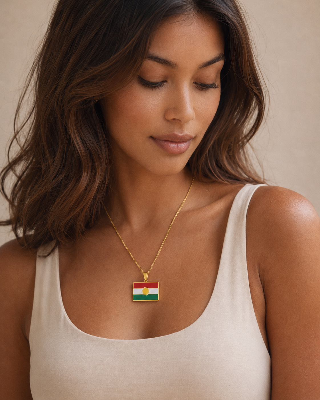 Kurdistan-Flaggenanhänger aus Edelstahl in Gold, rechteckig – getragen von einer jungen Frau im cremefarbenen Top, Porträt-Nahaufnahme