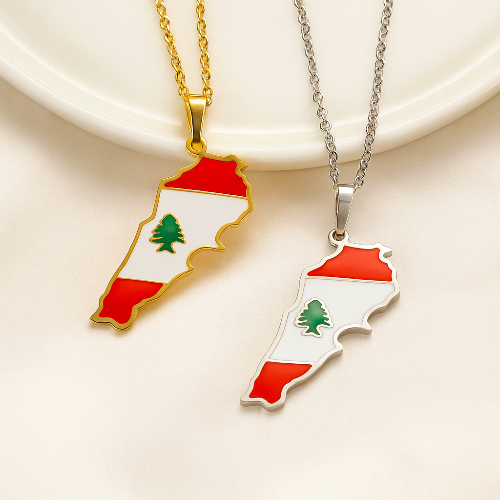 Zwei Halsketten mit Libanon-Karten-Anhänger in den Landesfarben Rot, Weiß und Grün mit Zeder – einmal in Gold und einmal in Silber – auf hellem Hintergrund