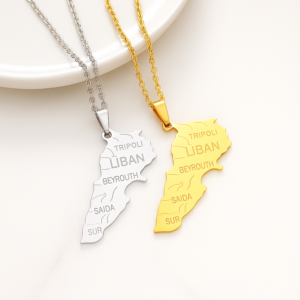 Zwei Halsketten mit Libanon-Karten-Anhänger mit gravierten Städtenamen wie Tripoli, Beirut, Saida und Sur – in Gold und Silber – auf hellem Hintergrund