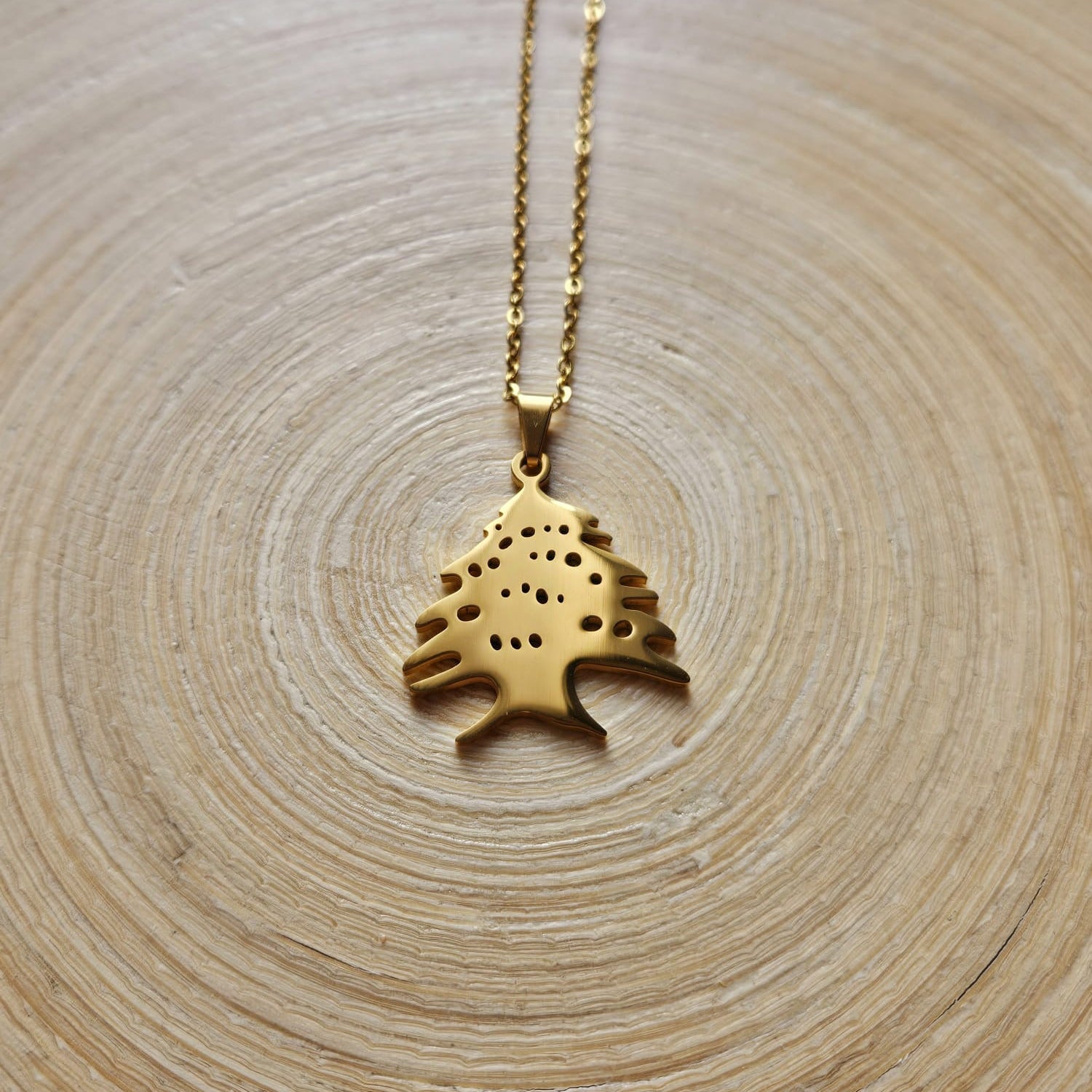 Goldene Halskette mit libanesischem Zeder-Anhänger, auf einer Holzscheibe liegend