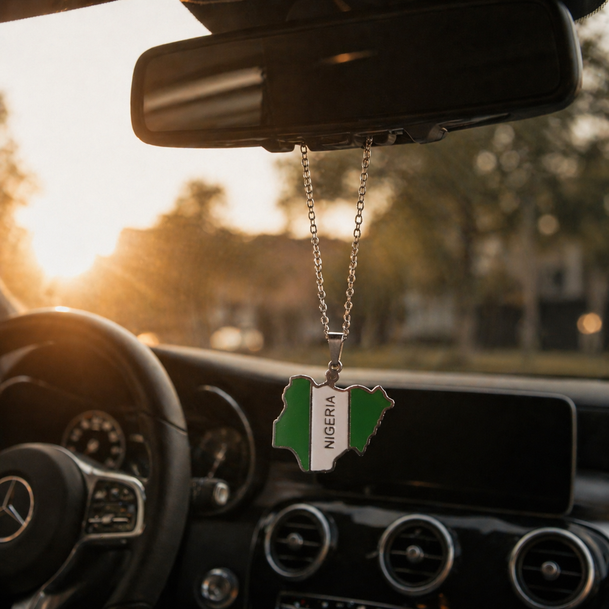 Nigeria Karte Flagge Anhänger in Silber mit NIGERIA Schriftzug hängt am Rückspiegel eines Mercedes – nigerianisches Schutzamulett fürs Auto